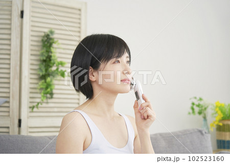 自宅で美顔器でフェイシャルケアをする女性 自宅で美顔器でフェイシャルケアをする女性 102523160