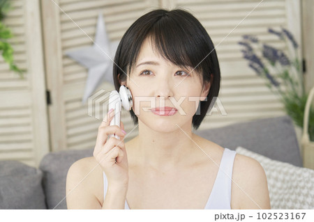 自宅で美顔器でフェイシャルケアをする女性 自宅で美顔器でフェイシャルケアをする女性 102523167