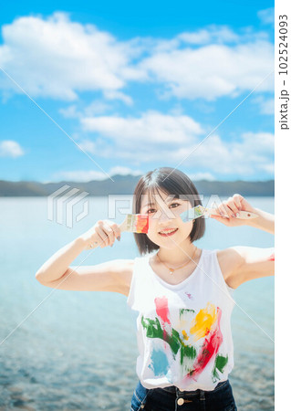 青空のもとカラフルなペンキで色を塗る美しい女性 102524093