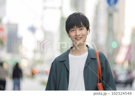 スマートフォンを持ってイヤホンをつけた20代の男性　カメラ目線　ポートレート 102524549