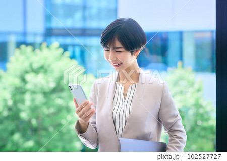 オフィスでスマホを操作する笑顔のミドルビジネスウーマン撮影協力：LINK FOREST 102527727