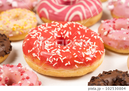 Donuts with red and pink glaze, top view. Lots of donuts, sweet and delicious food Donuts with red and pink glaze, top view. Lots of donuts, sweet and delicious food 102530804