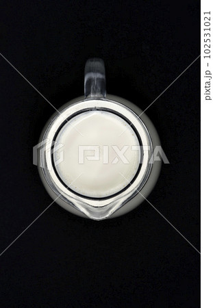 Glass milkman on a black background. A jug of milk. Milk in a vessel. 102531021