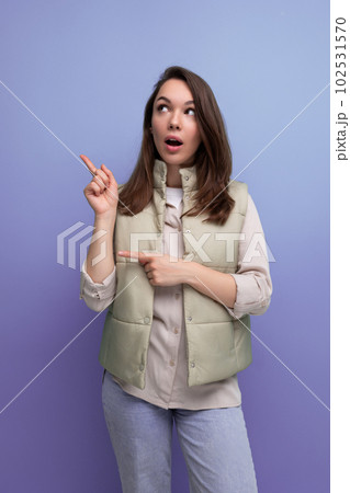 brunette young woman in a vest offers to look to the side pointing a finger brunette young woman in a vest offers to look to the side pointing a finger 102531570