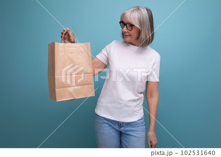 middle aged woman holding shopping bag on studio background 102531640