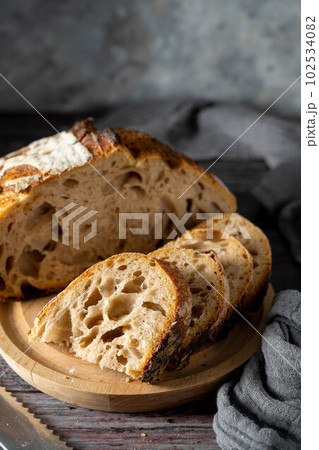 Sourdough homemade bread cut into slices on cutting board, dark moody food photo. Sourdough homemade bread cut into slices on cutting board, dark moody food photo. 102534082