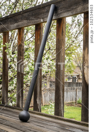 steel mace (or macebell) on a wooden deck, fitness concept using unconventional equipment, springtime scenery 102534603