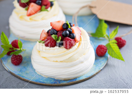 Pavlova cakes with cream and fresh berries 102537055