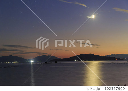 瀬戸内の夕暮れの空に沈む三日月 102537900