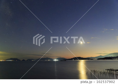 瀬戸内の夕暮れの空に沈む三日月 102537902