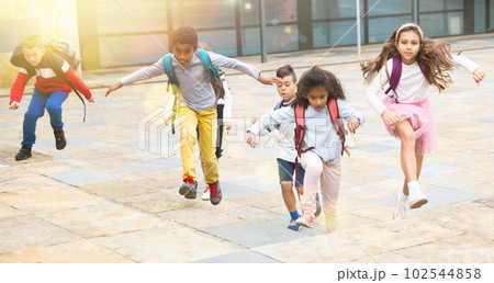 Team of positive schoolchildren running in race in the street 102544858