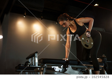 Sporty woman exercising with weight plate in the gym. 102545828