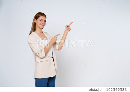 Young  woman pointing to empty copy space isolated on white background. 102546528