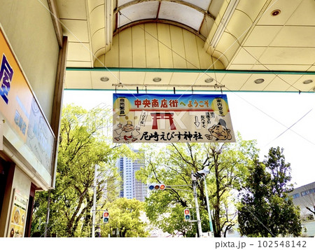 尼崎中央商店街アーケードにある尼崎えびす神社の垂れ幕越しに公園の緑が見える風景　兵庫県尼崎市 102548142