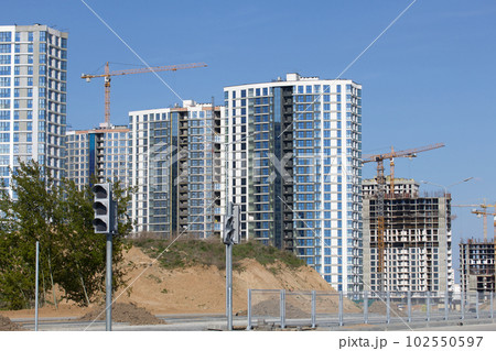 Construction site. Reinforced concrete frame of a multi-storey building and construction cranes. The final stage of construction. Against the background of the blue sky. 102550597