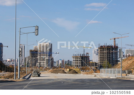 Construction site. Reinforced concrete frame of a multi-storey building and construction cranes. The final stage of construction. Against the background of the blue sky. Construction site. Reinforced concrete frame of a multi-storey building and construction cranes. The final stage of construction. Against the background of the blue sky. 102550598