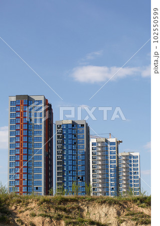 Construction site. Reinforced concrete frame of a multi-storey building and construction cranes. The final stage of construction. Against the background of the blue sky. Construction site. Reinforced concrete frame of a multi-storey building and construction cranes. The final stage of construction. Against the background of the blue sky. 102550599