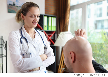 Woman doctor trichologist examining male patient with hair loss problem Woman doctor trichologist examining male patient with hair loss problem 102551041