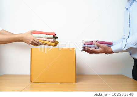 Donation, Charity, Volunteer, Giving, Delivery and Home Moving Concept. Hand holding Clothes into cardboard box at home for support and help poor, refugee and homeless people. Copy space for text 102551549