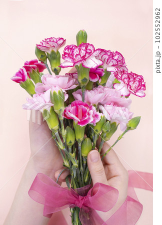 Two woman's hands holding a bouquet of carnations 102552962