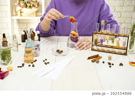 Preparation of perfumes from natural ingredients, aromatherapy. Fresh flowers and natural ingredients in chemical test tubes and flasks 102554986