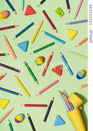 Open Yellow pencil case with Colored Pencils and rubber erasers background pattern on light green. Back to School or drawing and creativity concept. Copy space in center. Top view Open Yellow pencil case with Colored Pencils and rubber erasers background pattern on light green. Back to School or drawing and creativity concept. Copy space in center. Top view 102555238
