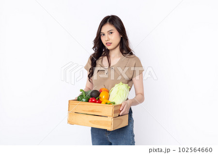 Cheerful smiling Asian woman holding a wooden box of vegetables after shopping isolated on a white background 102564660