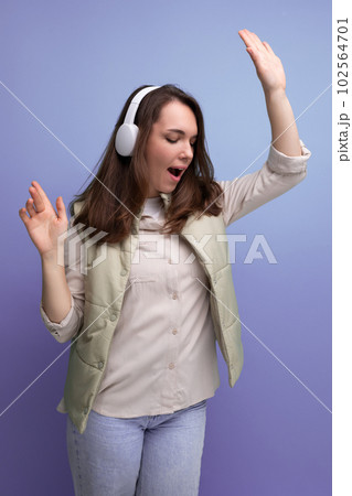 energetic young brunette woman relaxing to music using headphones and mobile phone 102564701