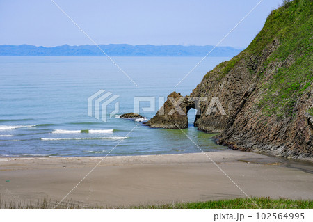 佐渡島を背景に越後七浦シーサイドライン角海浜（かくみはま）の海蝕洞 102564995