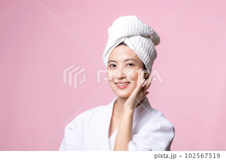 Beautiful young asian woman happy with clean face skin in towel and bathrobe, spa suit on pink background. Skincare, treatment, wellness therapy, facial care, beauty female health, cosmetology concept 102567519