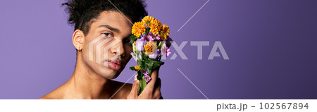 Nacked hispanic male with flowers in hand posing on purple background. Transgender man nude torso 102567894
