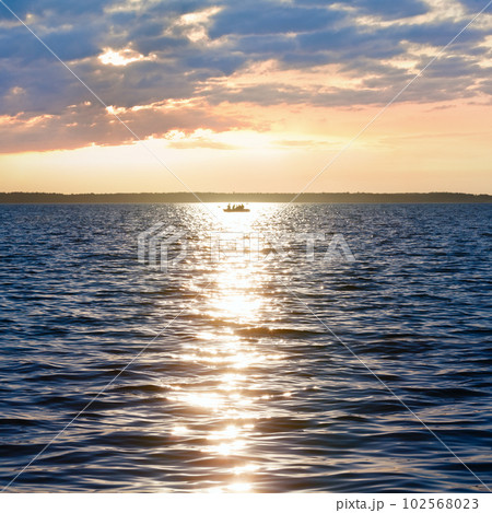 Sun track and fishing boat on lake surface. Sun track and fishing boat on lake surface. 102568023