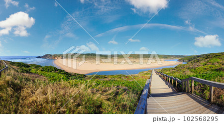 Atlantic ocean coast, wooden walkway to Amoreira beach and Aljezur river summer view, Algarve region, Portugal. 102568295