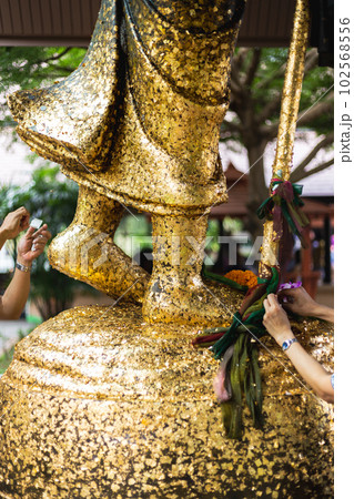 People attached gold leaf to the statue of Buddha People attached gold leaf to the statue of Buddha 102568556