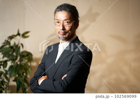 腕組みをしながら視線を向けるクールなシニア男性 102569099