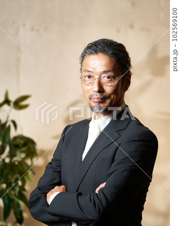腕組みをしながら視線を向けるクールなシニア男性 102569100