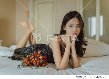 ベッドに寝そべる若い女性のファッションポートレート ベッドに寝そべる若い女性のファッションポートレート 102569175