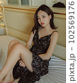 ベッドに座る若い女性のファッションポートレート 102569176