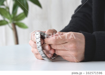 腕時計を持つ男性の手元 102571596