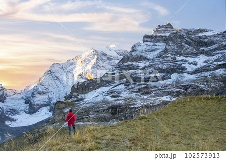 Sporty woman standing in front of snow mountains and enjoying view of Switzerland nature. Wanderlust, sport, beauty in nature. 102573913