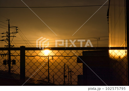 夕焼けで黄色く霞む空と建物のシルエット 夕焼けで黄色く霞む空と建物のシルエット 102575795