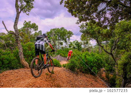 Unrecognisable mountain biker rides a beautiful trail on red earth, Massa Marittima, Tuscany, Italy 102577235