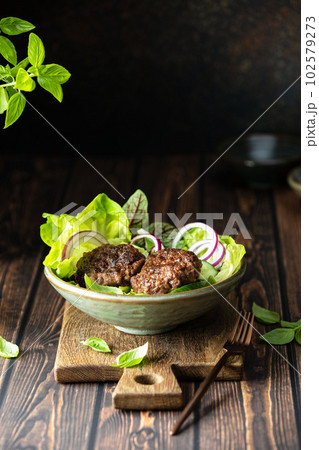 Grilled beef patties served with fresh crusty green salad Grilled beef patties served with fresh crusty green salad 102579273