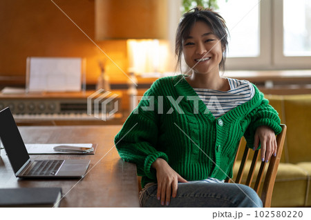 Asian girl in green shirt at home looking contented and relaxed Asian girl in green shirt at home looking contented and relaxed 102580220