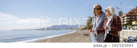 Cheerful mature ladies relaxing outdoors at coastline 102583093