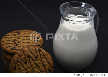 A jug of milk and oatmeal cookies. Delicious breakfast. Oatmeal cookies with milk. A jug of milk and oatmeal cookies. Delicious breakfast. Oatmeal cookies with milk. 102583541