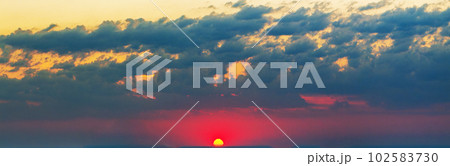 A celestial panorama at dawn. Red sun on the horizon, clouds, bright colors A celestial panorama at dawn. Red sun on the horizon, clouds, bright colors 102583730