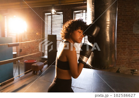 Women self defense girl power. African american woman fighter resting after fight training on boxing ring. Girl tired after punching boxing bag. Training day in gym. Strength fit body workout training 102586627