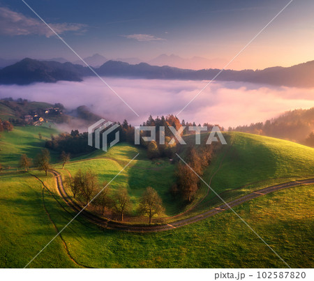 Aerial view of alpine meadows and mountains in clouds at sunrise 102587820