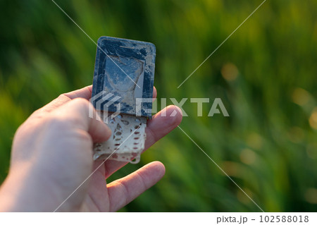 E-waste recycling - old, damaged cell phone in hand. Copy space for text. E-waste recycling - old, damaged cell phone in hand. Copy space for text. 102588018